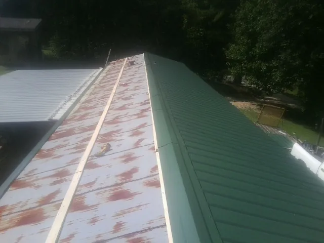 Old rusted panels beside newly installed green metal roofing — Wind Damage Roof Repair by Roofing Brothers in Carmine