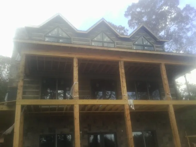 Dormers and porch framing on a large log home under construction — Roof Coating work by our crew in Carmine