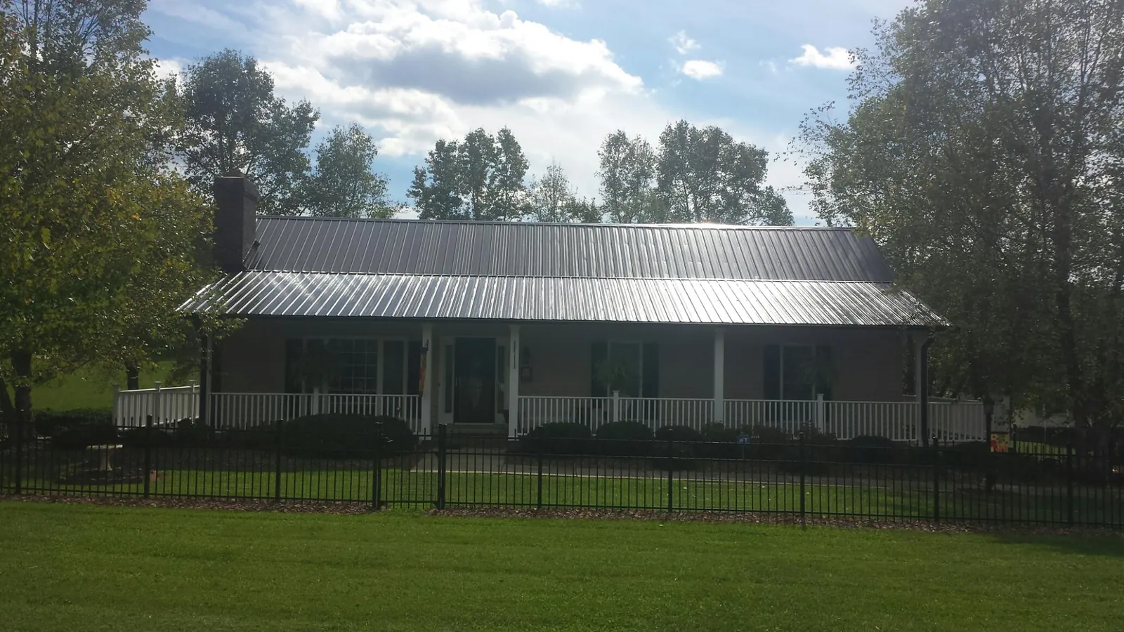 Gray metal roof on a brick ranch with a full width front porch — Gutter Guard Installation work by our crew in Carmine