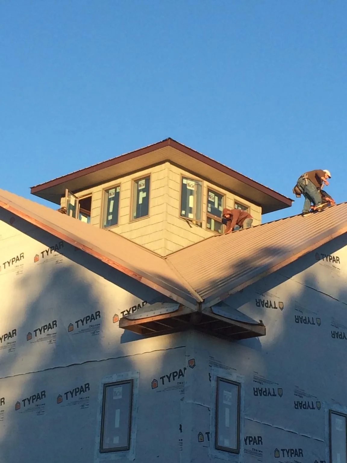 Roofers working around a rooftop cupola on a new metal roof at sunset — Roof Waterproofing in Carmine by Roofing Brothers